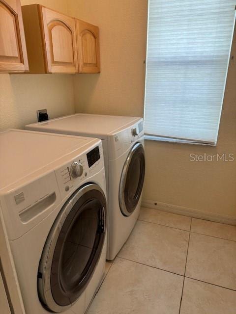 washroom featuring cabinets, light tile patterned floors, and washing machine and dryer