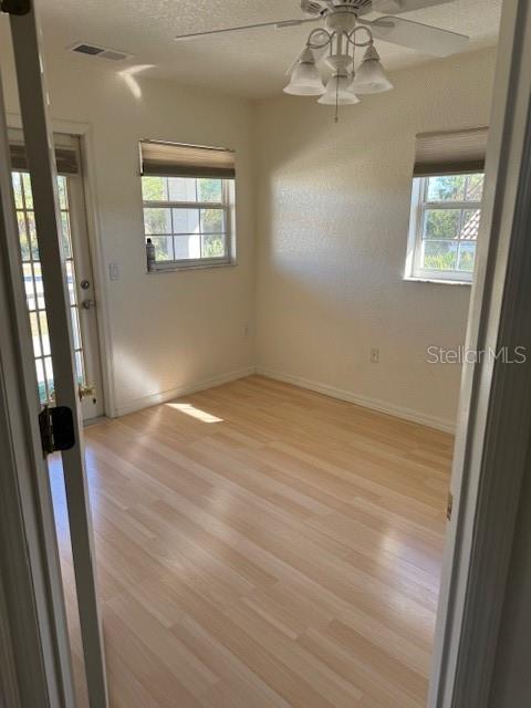 empty room with ceiling fan, a healthy amount of sunlight, and light hardwood / wood-style floors