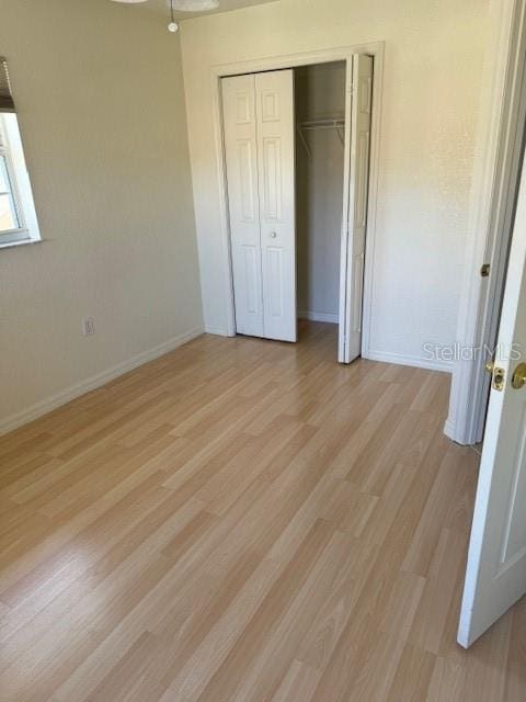 unfurnished bedroom with light hardwood / wood-style flooring and a closet