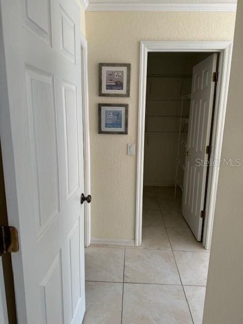 hall featuring ornamental molding and light tile patterned floors