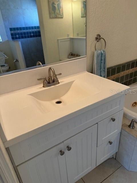 bathroom featuring toilet, vanity, tile patterned floors, and tile walls