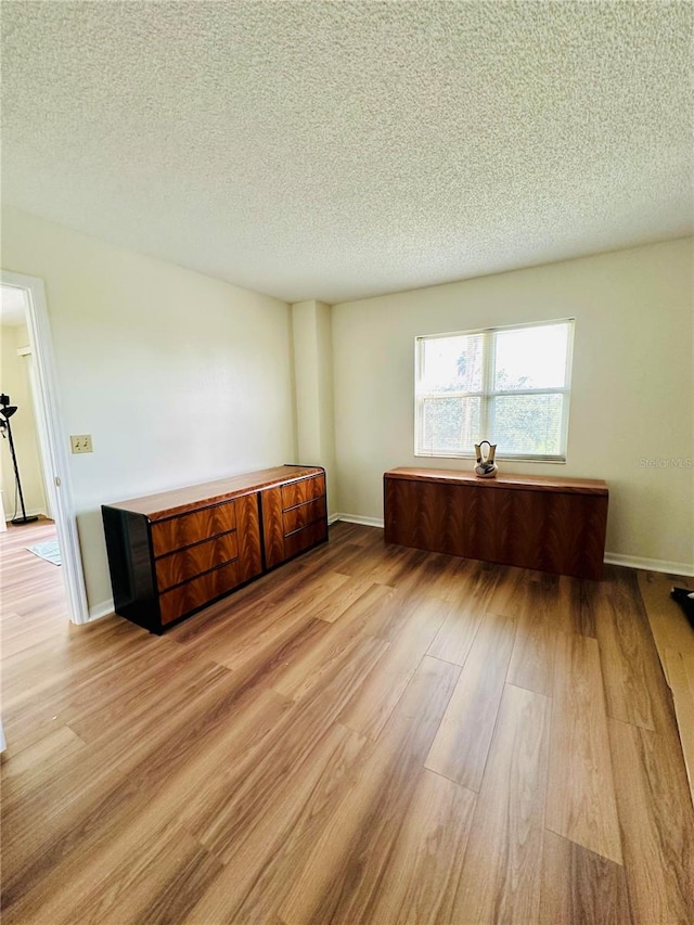 unfurnished room featuring a textured ceiling and light wood-type flooring