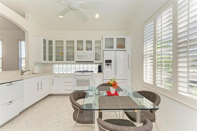 kitchen featuring white cabinets, light tile patterned floors, white appliances, and sink