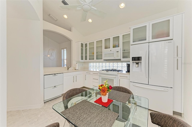 kitchen with white appliances, sink, light tile patterned floors, white cabinets, and lofted ceiling