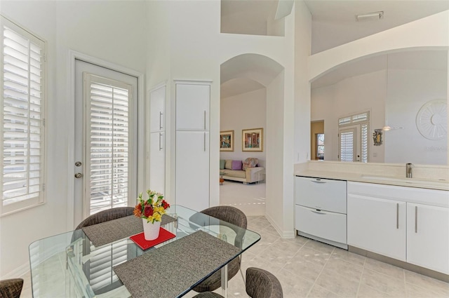 dining space with light tile patterned flooring, lofted ceiling, and sink