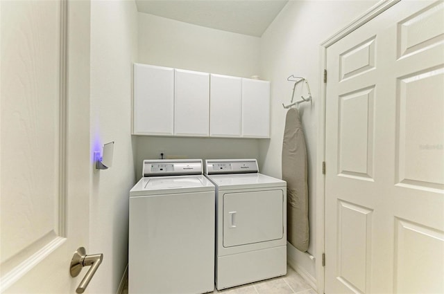 laundry area with cabinets, light tile patterned floors, and washing machine and clothes dryer