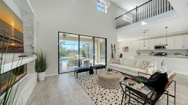 living room featuring a stone fireplace, crown molding, light hardwood / wood-style flooring, and a towering ceiling