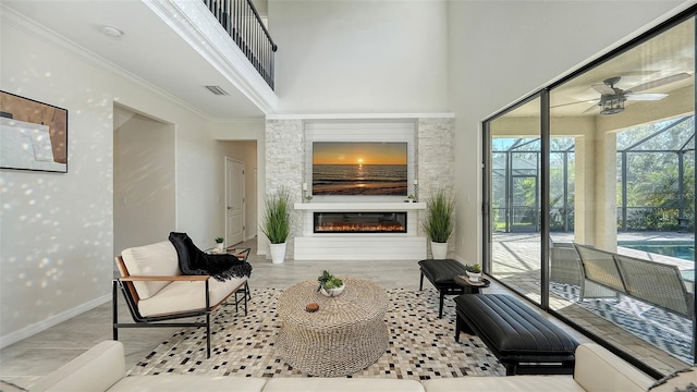 living room with ceiling fan, crown molding, and a high ceiling