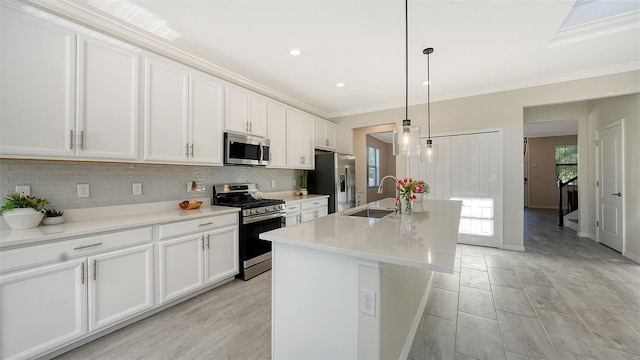 kitchen featuring a kitchen island with sink, sink, decorative light fixtures, white cabinetry, and stainless steel appliances