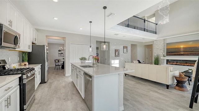 kitchen with stainless steel appliances, white cabinetry, a center island with sink, and sink