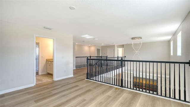 corridor featuring light hardwood / wood-style floors and an inviting chandelier