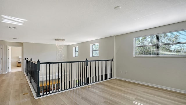 empty room with a textured ceiling, light wood-type flooring, and plenty of natural light