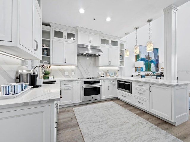 kitchen featuring white cabinetry, light stone counters, decorative light fixtures, appliances with stainless steel finishes, and light wood-type flooring