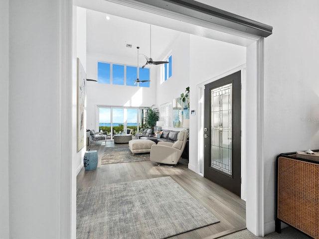 entrance foyer with ceiling fan, light hardwood / wood-style floors, and a high ceiling