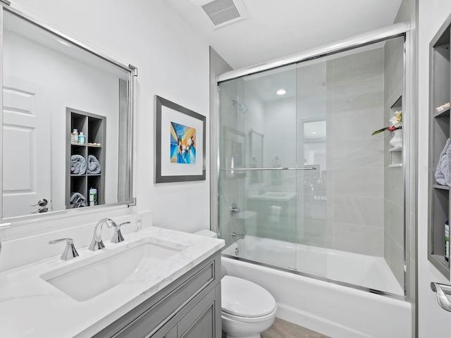 full bathroom with vanity, toilet, and bath / shower combo with glass door