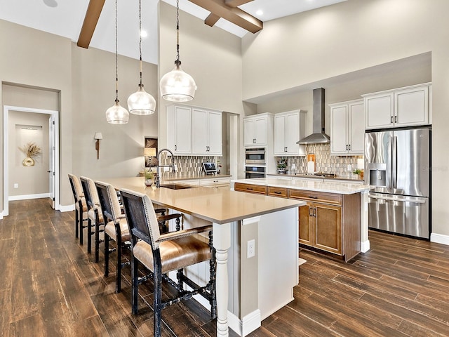 kitchen with white cabinets, wall chimney range hood, sink, and appliances with stainless steel finishes