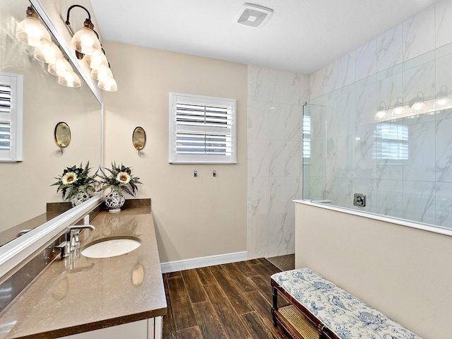 bathroom with a tile shower and vanity