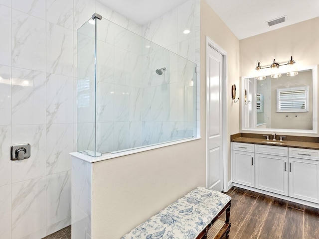 bathroom with a tile shower and vanity