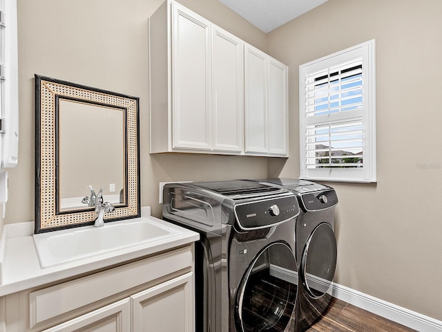 clothes washing area with hardwood / wood-style floors, washing machine and dryer, sink, and cabinets