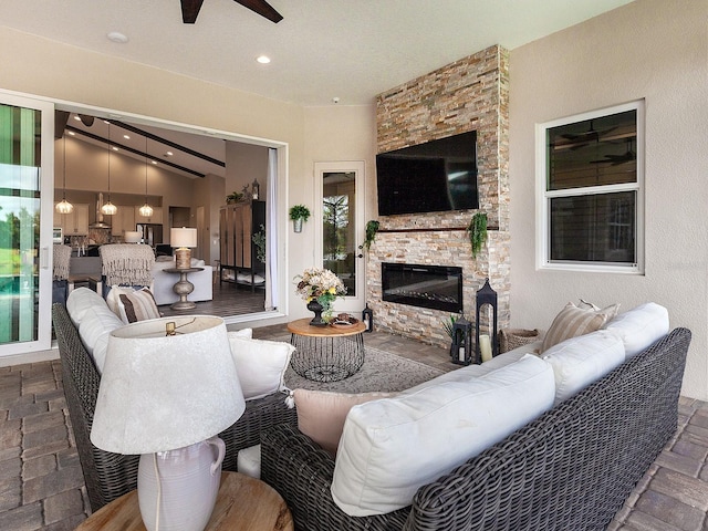 living room with vaulted ceiling, ceiling fan, and an outdoor stone fireplace