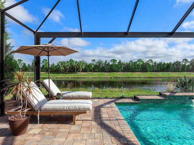 view of pool featuring glass enclosure, pool water feature, a water view, and a patio