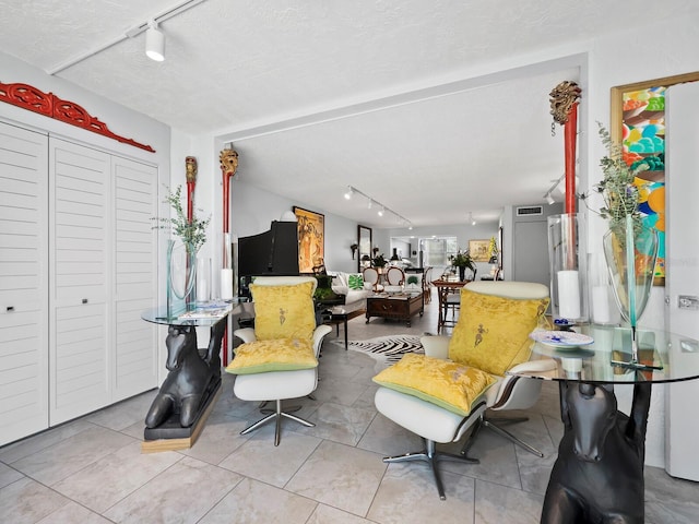 living room featuring rail lighting, light tile patterned flooring, and a textured ceiling