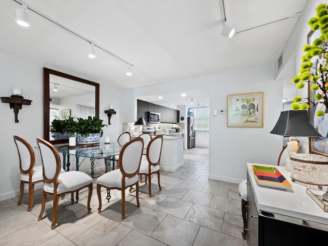 dining area featuring light tile patterned floors and rail lighting