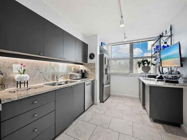 kitchen featuring appliances with stainless steel finishes, tasteful backsplash, track lighting, sink, and light tile patterned floors