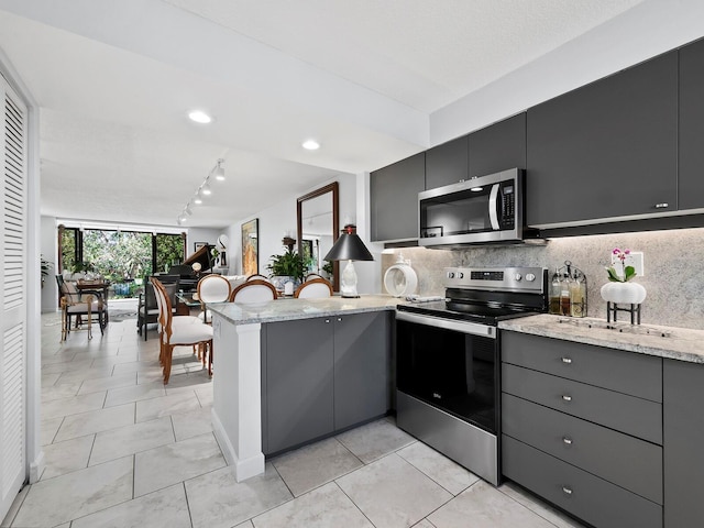 kitchen with gray cabinetry, decorative backsplash, kitchen peninsula, and stainless steel appliances