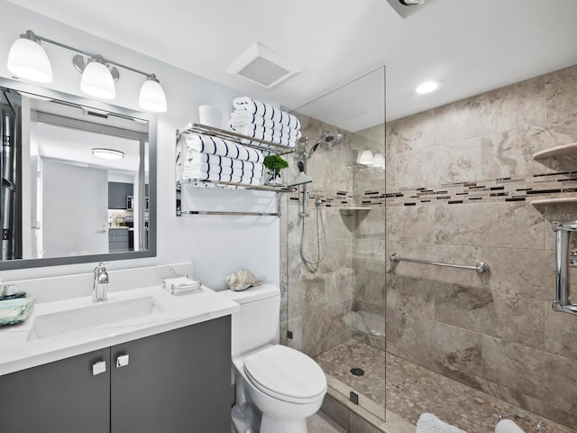 bathroom featuring tiled shower, vanity, and toilet