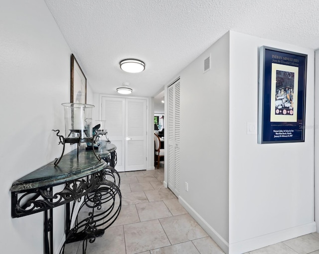 corridor featuring a textured ceiling and light tile patterned flooring