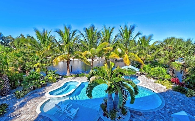 view of swimming pool featuring a patio area, an in ground hot tub, and a water view