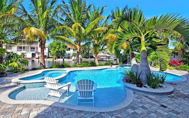 view of pool featuring a water view and an in ground hot tub