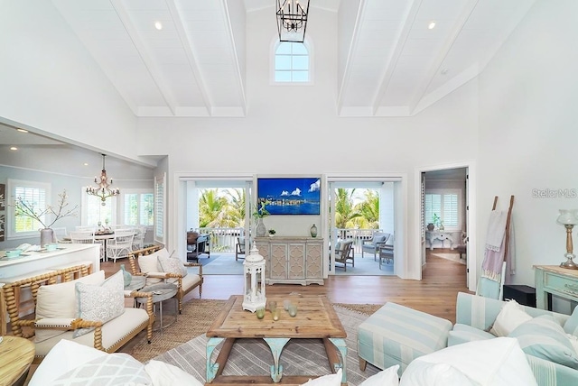 living room with hardwood / wood-style floors, high vaulted ceiling, an inviting chandelier, and beam ceiling