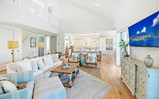 living room featuring beamed ceiling, light wood-type flooring, and high vaulted ceiling