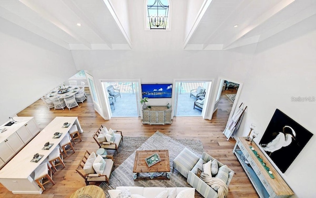 living room with a towering ceiling, beamed ceiling, and light wood-type flooring