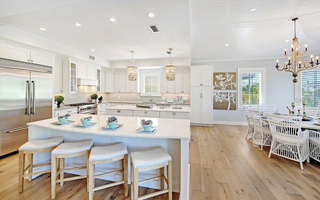 kitchen with a spacious island, high end appliances, and white cabinetry