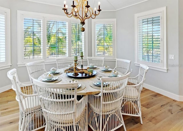 dining room with crown molding, light hardwood / wood-style flooring, and an inviting chandelier