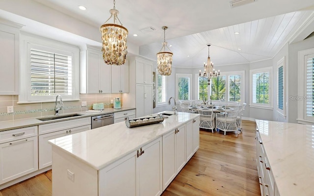 kitchen with sink, stainless steel dishwasher, a healthy amount of sunlight, and an island with sink