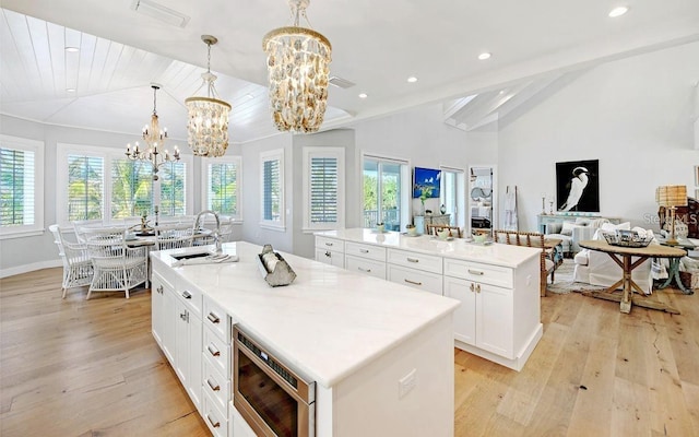 kitchen with stainless steel microwave, a kitchen island with sink, a healthy amount of sunlight, sink, and hanging light fixtures