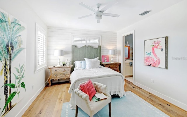 bedroom with ceiling fan, light hardwood / wood-style floors, and wood walls