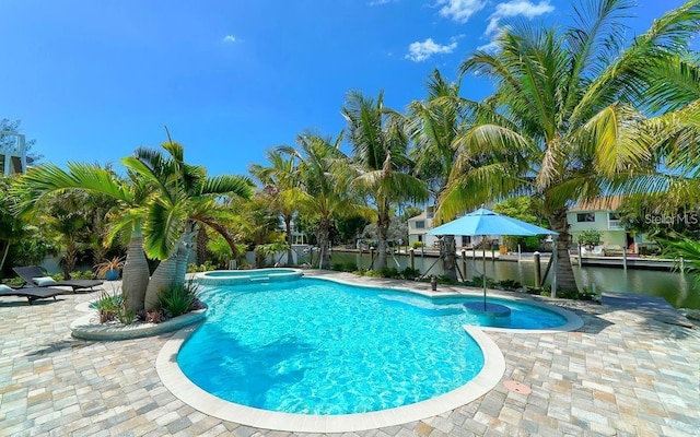 view of swimming pool featuring an in ground hot tub, a water view, and a patio area