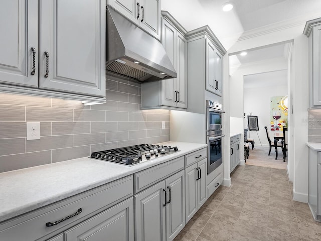 kitchen with decorative backsplash, stainless steel appliances, crown molding, light tile patterned floors, and gray cabinets