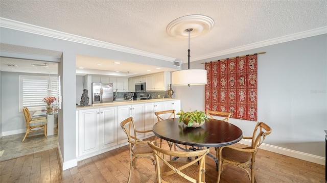 dining room featuring crown molding, light hardwood / wood-style flooring, and a textured ceiling