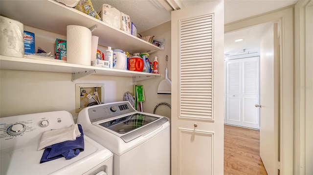 laundry room featuring washing machine and dryer, light hardwood / wood-style floors, and a textured ceiling