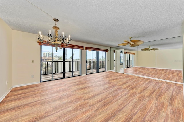 unfurnished living room featuring a textured ceiling, light hardwood / wood-style floors, and ceiling fan with notable chandelier