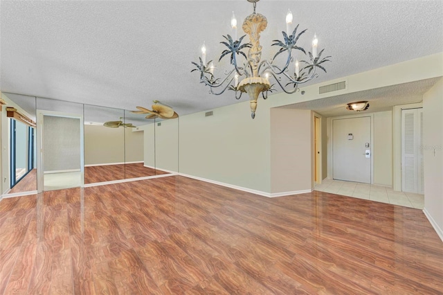 interior space with ceiling fan with notable chandelier, a textured ceiling, and hardwood / wood-style flooring