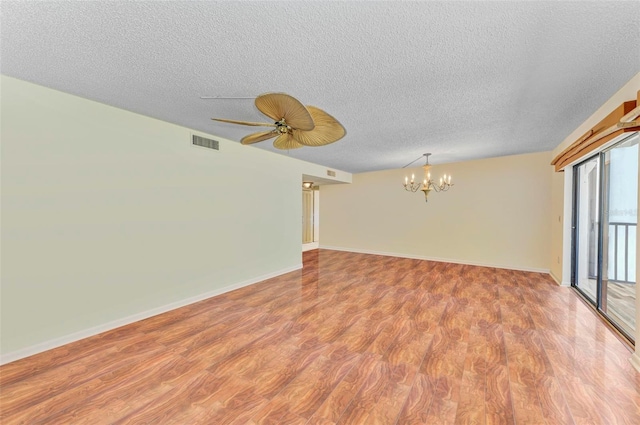 spare room featuring ceiling fan with notable chandelier, wood-type flooring, and a textured ceiling