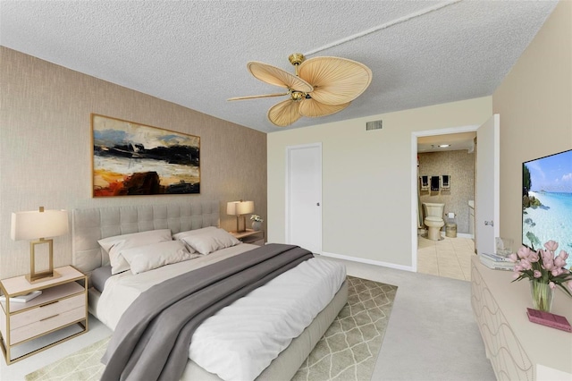 bedroom featuring ensuite bath, ceiling fan, light colored carpet, and a textured ceiling