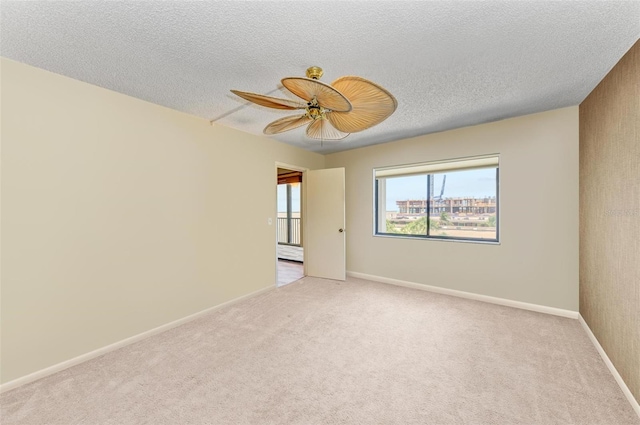 empty room featuring a textured ceiling, ceiling fan, and light carpet